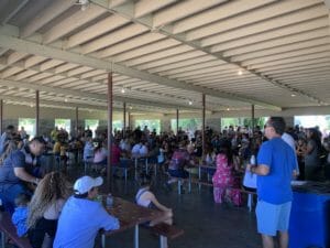 A crowd of people sitting at tables in a covered area with Supreme Boats.