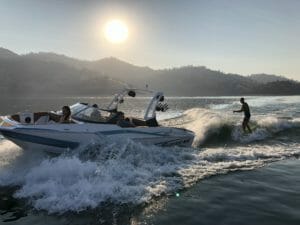 A man is riding a Supreme speed boat in the water.