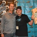 Two men posing for a picture in front of a Supreme banner.