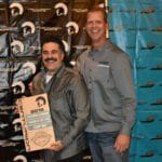 Two men standing in front of a wall with a Supreme Boats plaque.