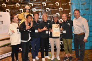 A group of people posing for a picture in front of a Supreme banner.