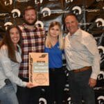 A group of people posing with a Supreme Boats plaque for a picture.