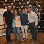 A group of people posing for a picture with a Supreme Boats plaque.