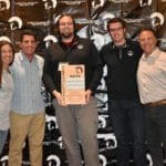 A group of people posing in front of a Supreme banner.