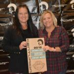 Two women standing in front of a Supreme Boats plaque.