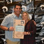 A couple posing for a picture in front of a Supreme banner.