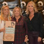 Three women standing in front of a wall with Supreme Boats plaque.