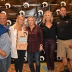 A group of people posing for a picture in front of a Supreme banner.