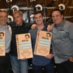 Four men are posing for a picture holding Supreme signs.