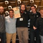 A group of men standing in front of a Supreme Boats banner.
