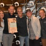 A group of people posing for a picture with a plaque at Supreme Boats.
