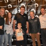 A group of people posing in front of a Supreme Boats banner.