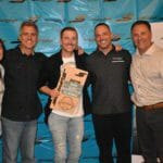 A group of people posing in front of a Supreme banner for a picture.