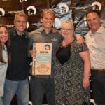 A group of people posing for a picture in front of a Supreme banner.