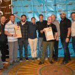 A group of people posing for a picture in front of a Supreme banner.