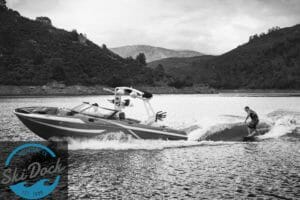 A man is wakeboarding behind a Supreme boat.