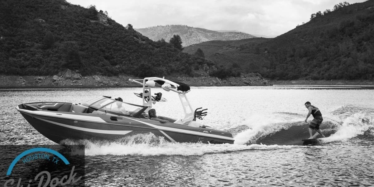 A man is wakeboarding behind a Supreme boat.