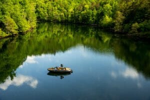 A man is floating in a Supreme boat on a river.