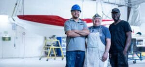 Three men standing in front of a boat.