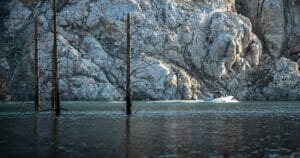 A Supreme boat in the middle of a lake near a rocky cliff.