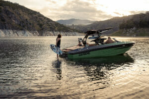 Surfer on the back of a Supreme S240 boat in the water