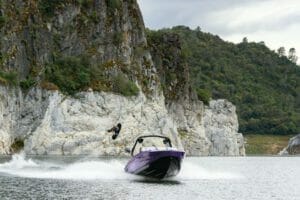 A person is riding a Supreme boat near a cliff.