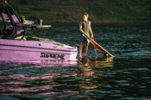 Wake surfer standing on swim step of purple S220 Supreme boat