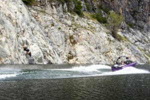 Purple S220 Supreme boat cruising next to shore