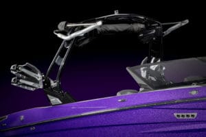 Close-up of a metallic purple 2026 Supreme S220 speedboat's upper side, featuring a black wakeboard tower with racks and folded canopy against a dark background.