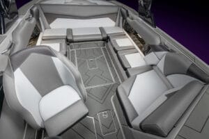 A modern 2026 Supreme S220 boat interior featuring gray and white cushioned seating, geometric-patterned flooring, and built-in speakers.