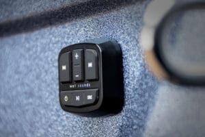 A close-up of a black Wet Sounds audio control panel with buttons for volume, power, and track selection, mounted on the textured surface of a Supreme S240.
