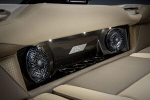 Close-up of a beige leather Supreme Boats S240 interior, featuring dual circular speakers, cup holders, and an S240 emblem on a glossy black panel.