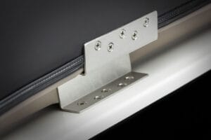 Close-up of a metal bracket with multiple screws securing a black and gray panel to a white surface, highlighting the quality construction found on Supreme S240 boats.