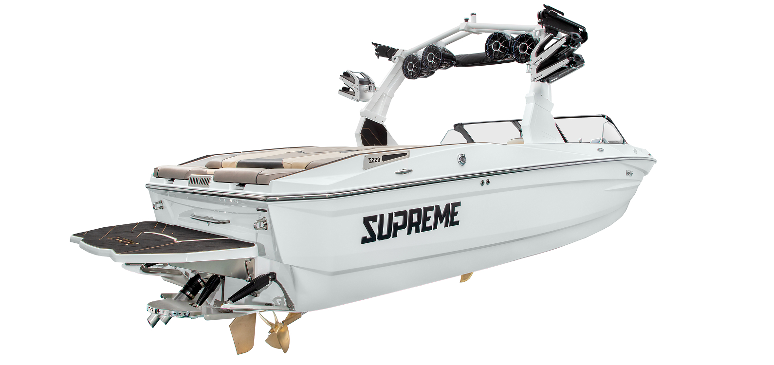 A white Supreme Towboats S220 wakeboard boat with tan seating, a black swim platform, and a tower equipped with speakers and racks, viewed from the rear side angle.