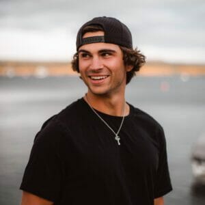 A young man wearing a black t-shirt and hat representing Supreme.