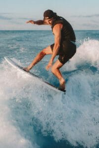A man surfing on a Supreme surfboard.