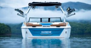 A Supreme boat on a serene lake with majestic mountains in the background.