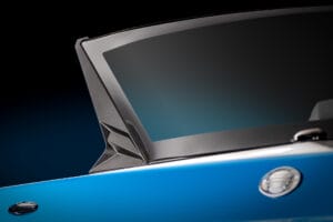 Close-up view of a blue car door with a small side mirror and a sleek, tinted window against a dark background, reminiscent of the streamlined design seen in Supreme S240 models.