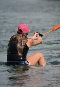 A woman is in the water with a surfboard, riding the waves.