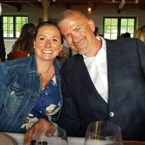 A man and woman posing for a photo at a restaurant with Wally.