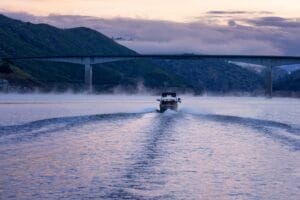 A Christmas event boat is traveling on the water near a bridge.