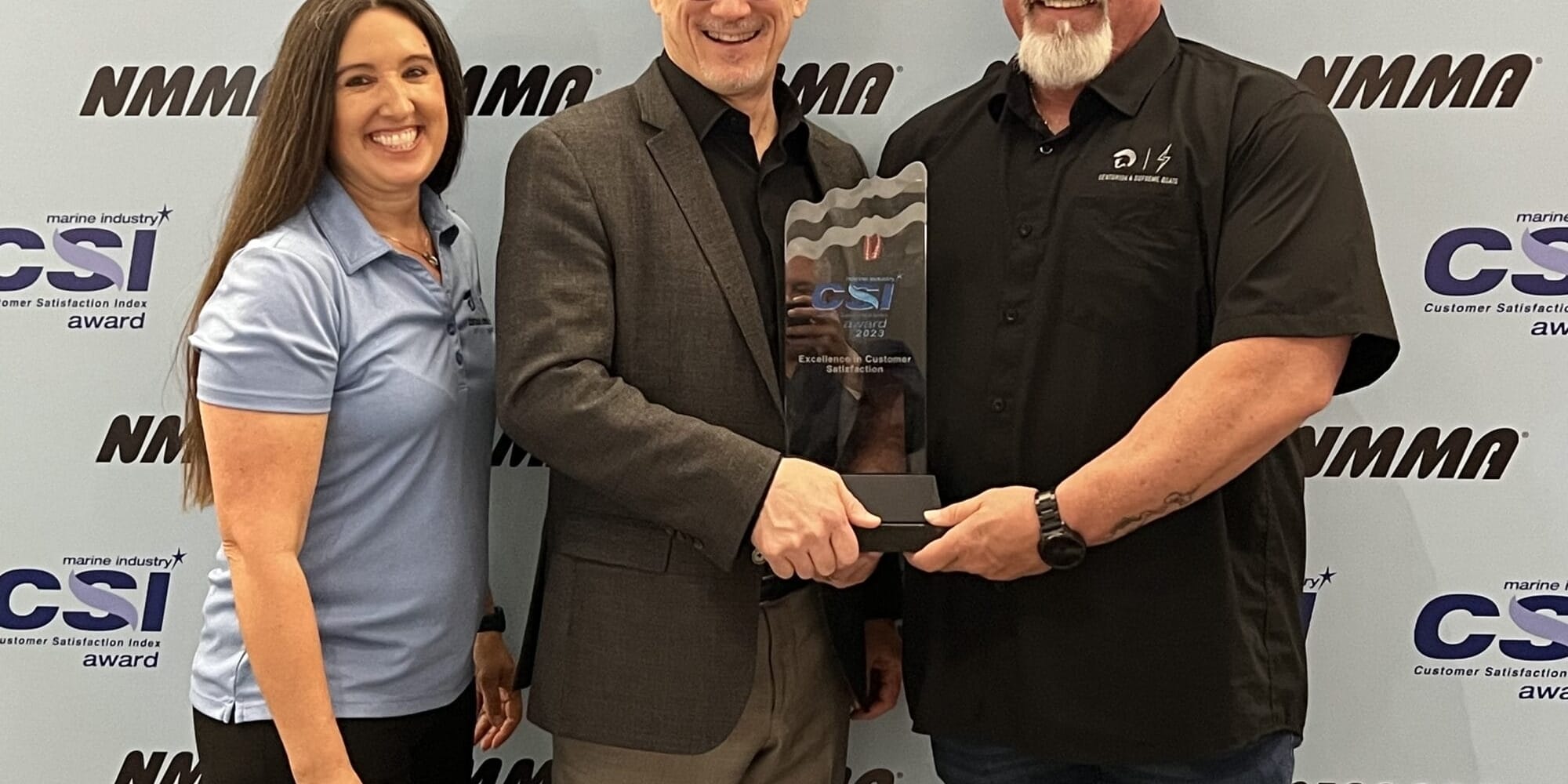 Three people standing in front of a banner with the NMMA Customer Satisfaction Excellence Award.