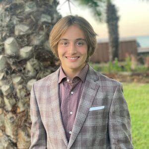Evan Hudson, a young man, smiling in front of a palm tree.