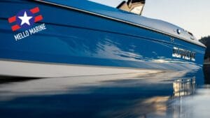 A blue boat, adorned with "Supreme" and "Mello Marine" logos, drifts like an auto draft on still water, mirroring the clear sky above.