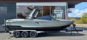 A sleek Centurion boat on a trailer parked outside a showroom with glass windows and signage, ready for transport.