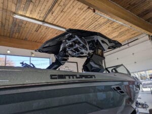 A Centurion boat in a showroom with a partially opened roof mechanism, under a wooden ceiling with fluorescent lights.