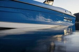 Close-up side view of a blue Supreme boat floating on calm water, its reflection shimmering below—an impressive showcase for any Florida dealership offering Supreme Boats.