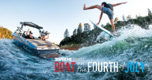 A person wakeboarding jumps near a Supreme Boat with passengers taking photos on a tree-lined lake; text reads, "Supreme Boat 4th of July Sale.